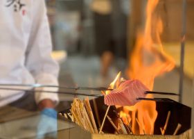 料理人が鮪を串にさして藁焼きにしている